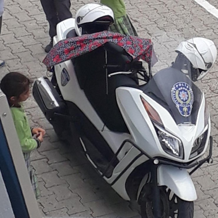Kırık şemsiyesiyle polis motosikletini ıslanmasın diye korudu