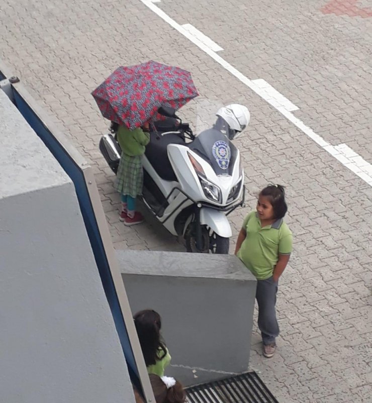 Kırık şemsiyesiyle polis motosikletini ıslanmasın diye korudu